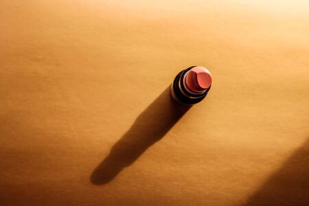 Beautiful modern minimal nude lipstick makeup cosmetic gold background with shadow.の写真素材