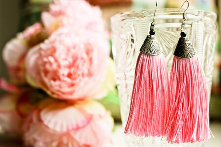 Bridesmaid earrings tassels and wedding bouquet on the blurred background. Beautiful wedding composition with bridal accessories.の写真素材