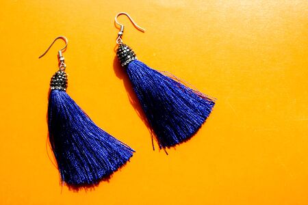 Closeup top view of two royal blue tassel earrings. The set is isolated on orange platform.の写真素材