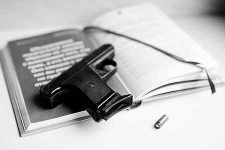 Gun and book. Detective novel concept. Pistols and bullet on the table. Black and white photo.の写真素材