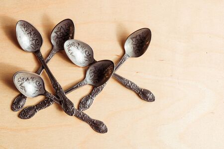 Ancient little spoons on a vintage wooden background. Vintage cutlery, kitchen utensils as concept, idea on a wooden background.の写真素材