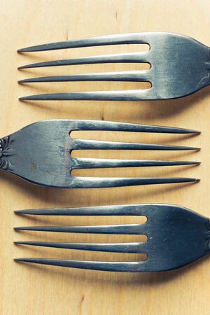Old rusty vintage set of three silver forks on a wooden texture background, close up view.の写真素材