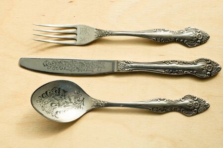 Beautiful vintage cutlery. Silver knive, fork and spoon on the natural wooden background.の写真素材
