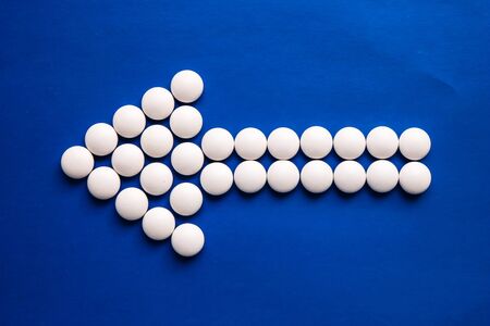 Arrow of white pills on blue background. Medicine concept.