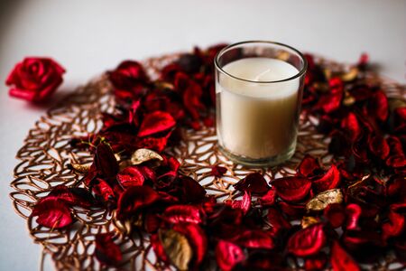 Rose petals and candle on white and gold mat. Romantic background.の写真素材