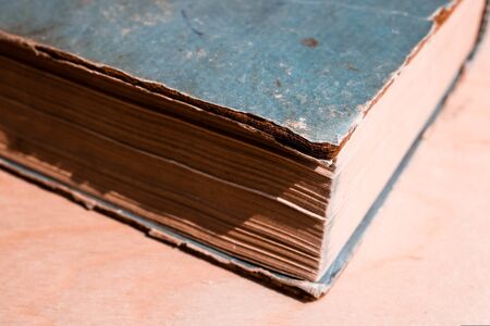 Front corner of old blue thick book with yellow pages close up isolated.の写真素材