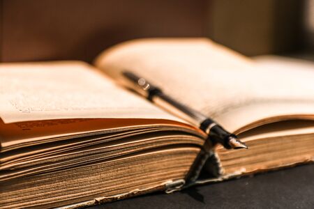Open ancient book with fountain pen on wooden table.の写真素材