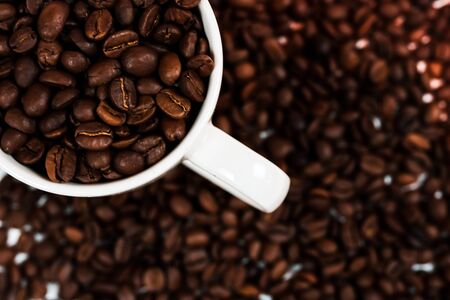 Cup of coffee close up with coffee beans on coffee beans background, top view with free space for...