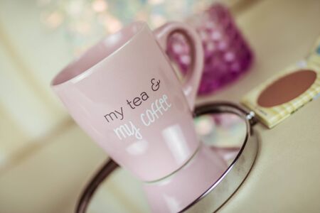 Pink cup of tea with christmas lights at backgroundの写真素材