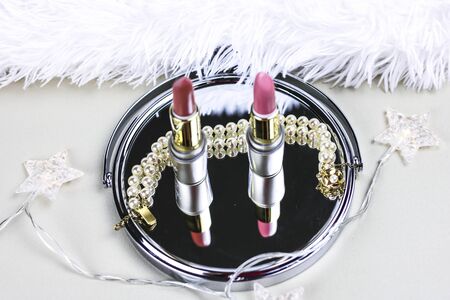 Silver cosmetic mirror and pink lipstick on white backgroundの写真素材