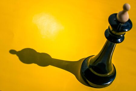 Chess piece king with shadow isolated on yellow background.の写真素材