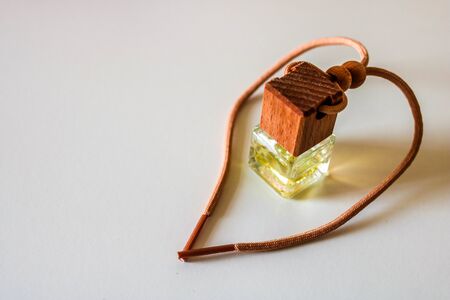 Car air perfume freshener bottle on the white plastic table. Little glass bottle with wooden lid and aromatic liquid.の写真素材