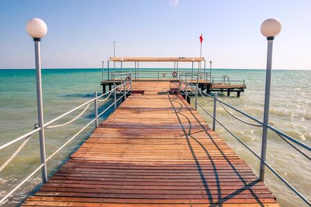 Wooden pier with street lamps, clear blue water in the Mediterranean Sea, holiday scenes with a sense of calm.の写真素材