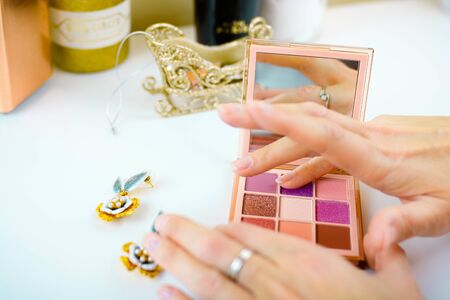 Swatches of eye shadows palette on a female fingers. white background. Woman puts swatch on her fingers.の写真素材