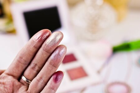Colorful eye shadow swatches on woman fingers. Eyeshadows with a metallic tint. Decorative cosmetics.の写真素材