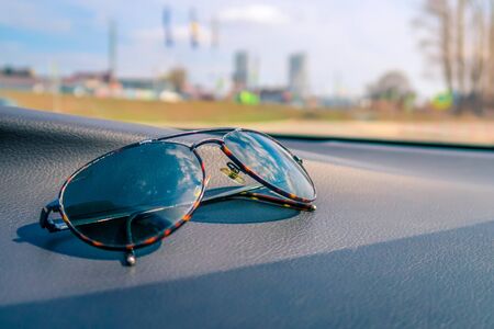 Elegant fashionable plastic men's sunglasses on interior car dashboard.の写真素材