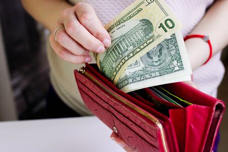 Debt and personal finances - closeup shot of a woman takes out several US dollar banknotes from her wallet and looking at it.の写真素材