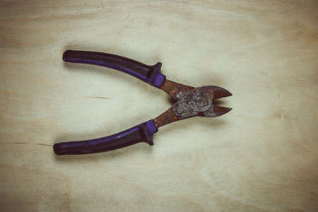 A worthless old pair of rusty wire cutters, isolated on wooden background. View from above.の写真素材
