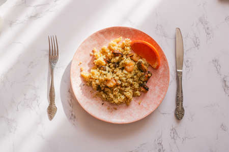 Seafood risotto in a pink plate on a white background, top view. Risotto with seafood. Tasty and healthy Mediterranean cuisine.の写真素材