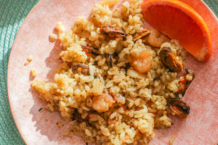 Seafood risotto close up on pink plate with citrus, healthy Italian food.の写真素材