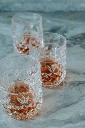 Three crystal glasses of whiskey on a stone table. Vertical photo.の写真素材
