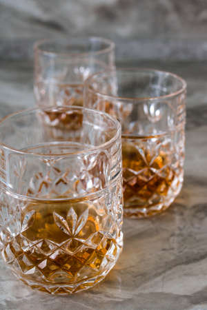 Three crystal glasses of whiskey on a stone bar counter. Vertical photo.