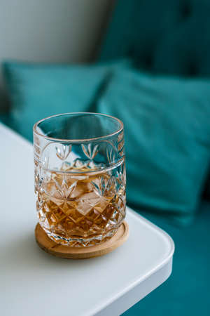 Modern still life in cold colors. Glass of whiskey with ice on the edge of the table.の写真素材