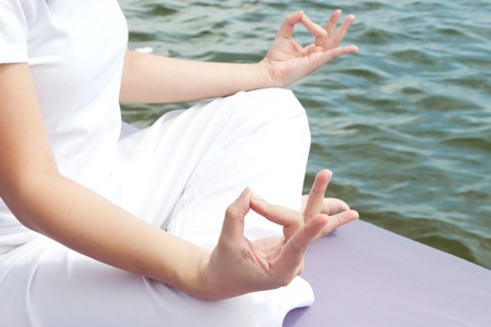 Hands of attractive young asian woman practicing yoga meditation at sunrise by the oceanの写真素材