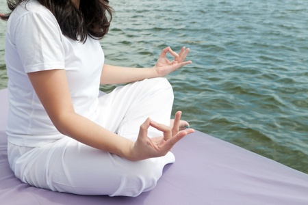 Attractive young asian woman practicing yoga meditation at sunrise by the oceanの写真素材