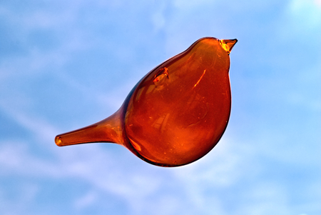 Stylized bird made from glass flying in the blue skyの写真素材