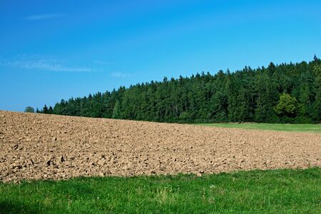 Landscape with meadow, plowed field, forest and blue skyの写真素材