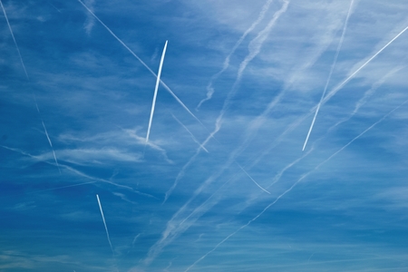 Pattern of airplane trails of condensed air on the blue skyの写真素材
