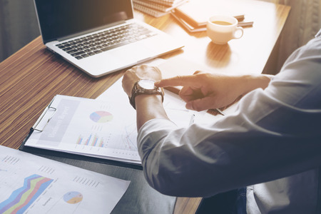 Hand pointing to the Watches and business documents on the table,Vintage filtersの写真素材