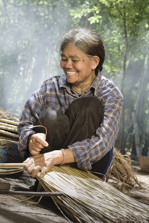 Smiling asian elderly woman weaves a roof.の写真素材