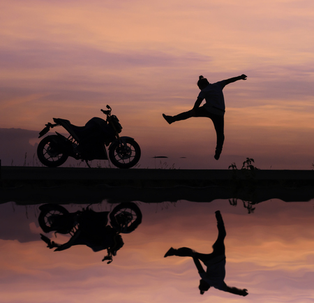 Silhouette of Man jump  and Motorcycles With a water reflection