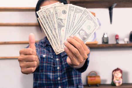 Happy  woman  with dollar bills showing thumb up.