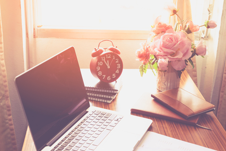 The clock, laptops, books and flower vase on the table.の写真素材