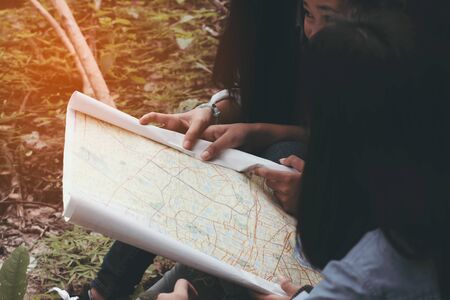 A group of traveler girls  searching direction on location map while traveling in the forest.の写真素材