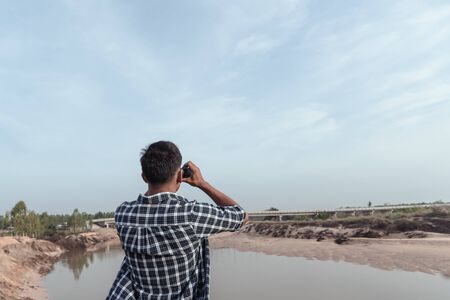 Tourist man looking through binoculars on the coast.の写真素材