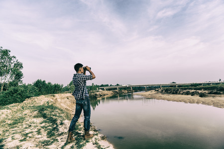 Tourist man looking through binoculars on the coast.の写真素材