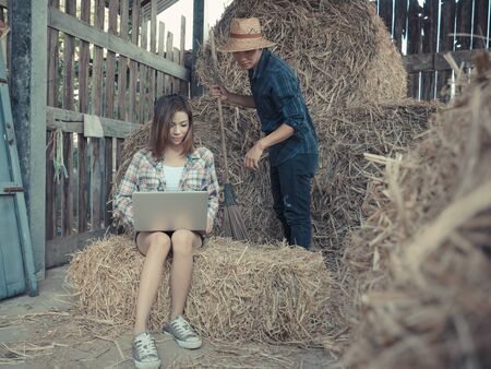 Farming couple with laptop,smartphone in hay shed.の写真素材