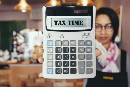  Tax time on calculator in  woman's hand in cafeの写真素材