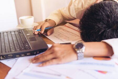 Exhausted and tired businessman sleeping in a cafe with laptop and coffee cup on the table.の写真素材