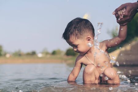Happy baby and father playing at the Lake. Happy family playing in water of Lake on a tropical resort at the nature.の写真素材