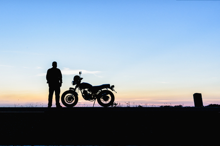 Silhouette of man and a motorcycle with sunset backgroundの写真素材