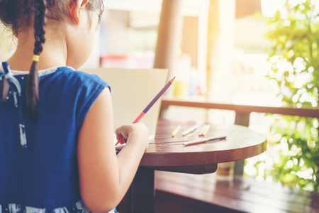 The girl's writing on paper during outdoor play.Learning outside the classroom to enhance skills to children.の写真素材