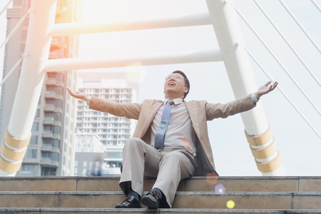 Businessmen with hands rise up sitting on the staircase, Bless from Godの写真素材