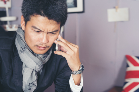 Seriously  asian businessman sitting in the cafe and using cell phone,business communication conceptの写真素材