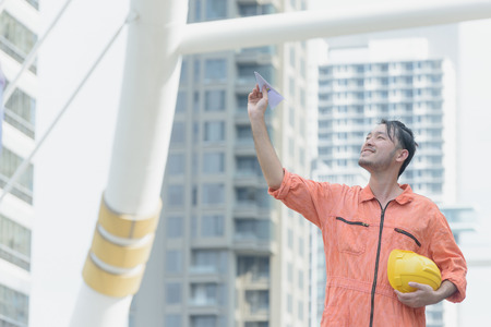Engineer holding a paper plane in the cityの写真素材