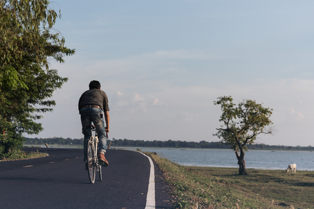 Man riding bike in the countryside on the road near the riverの写真素材